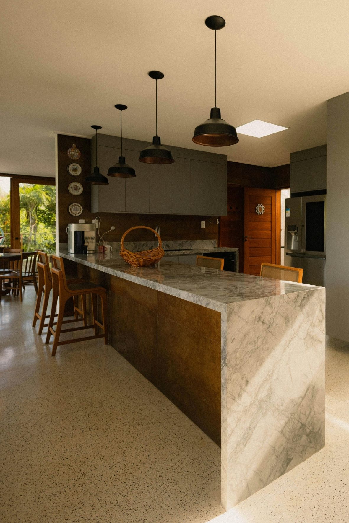 Cuisine contemporaine avec îlot central en bois clair, tabourets et hotte suspendue dans un intérieur résidentiel  à Deux-Montagnes